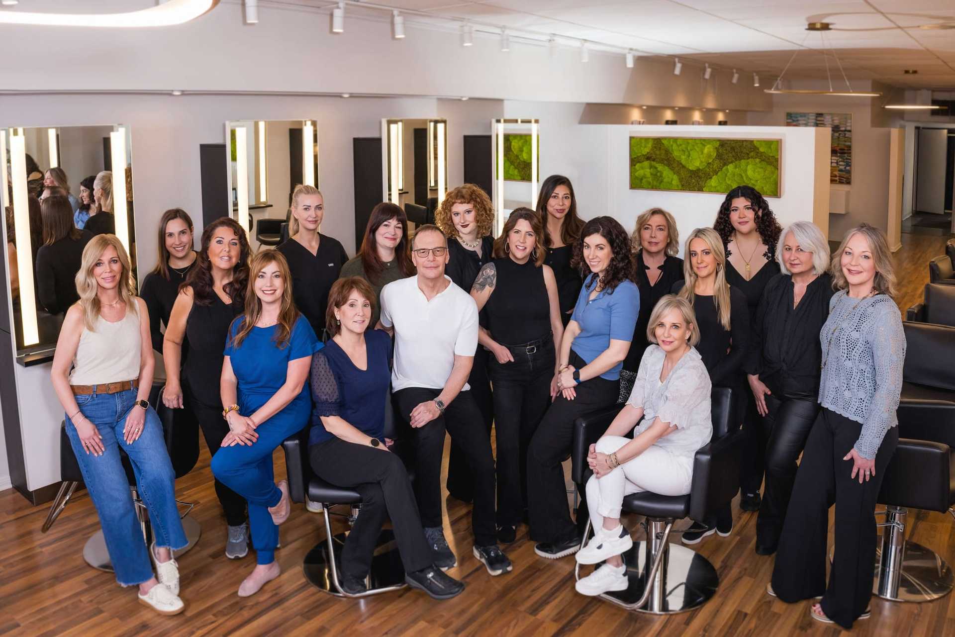 Group of salon staff posing together in a modern hair salon.