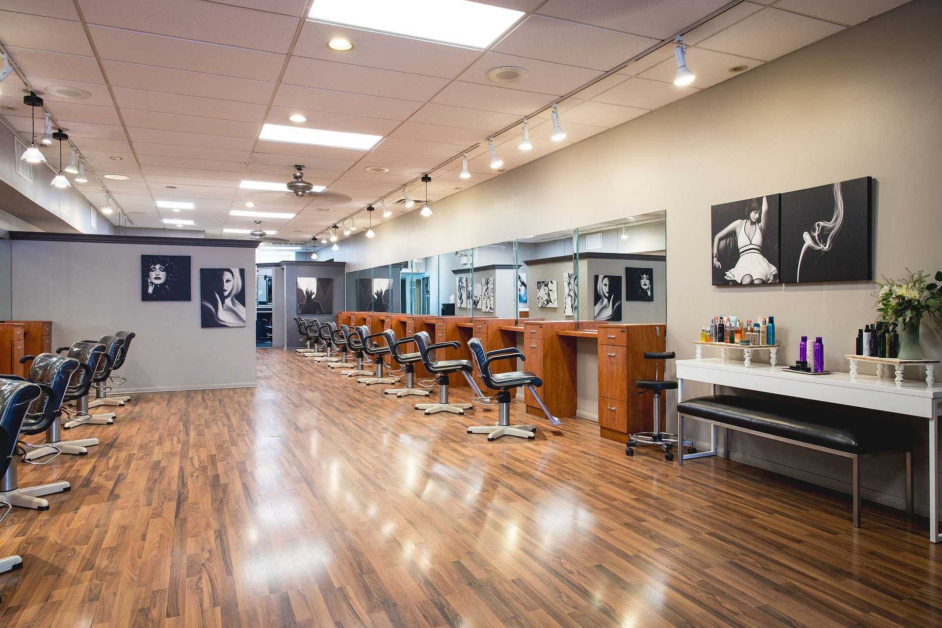Modern, spacious hair salon with hardwood floors, multiple styling stations, and art on the walls.