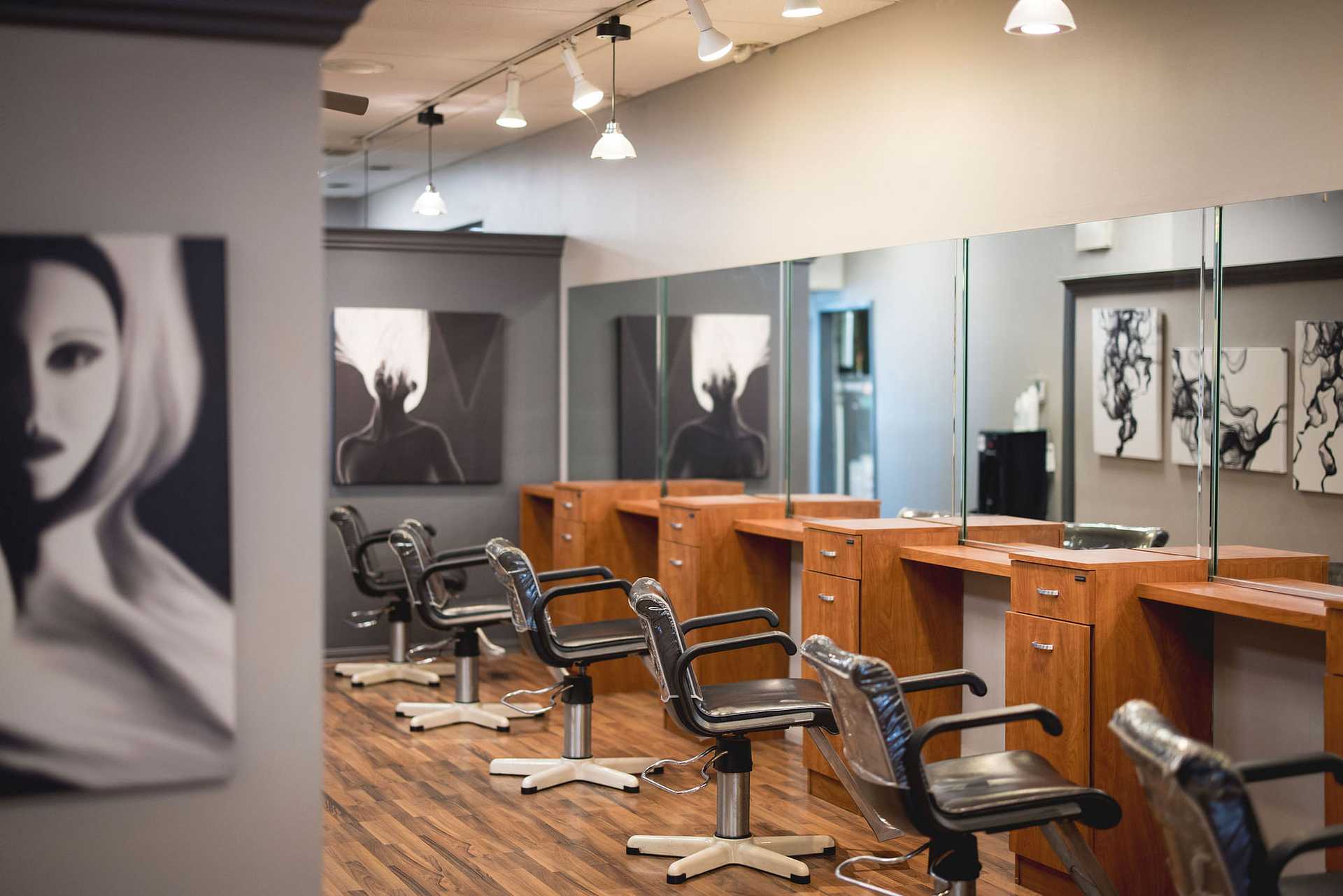Modern hair salon with empty chairs, mirrors, and abstract black-and-white art on the walls.
