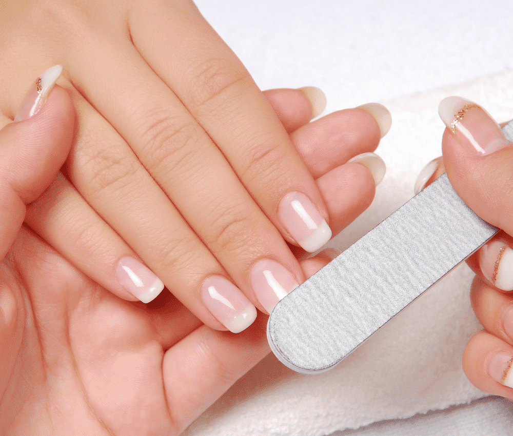 A person filing well-manicured nails with a nail buffer.