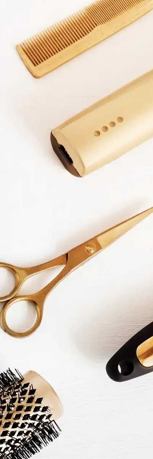 Golden hair styling tools arranged diagonally on a white background.