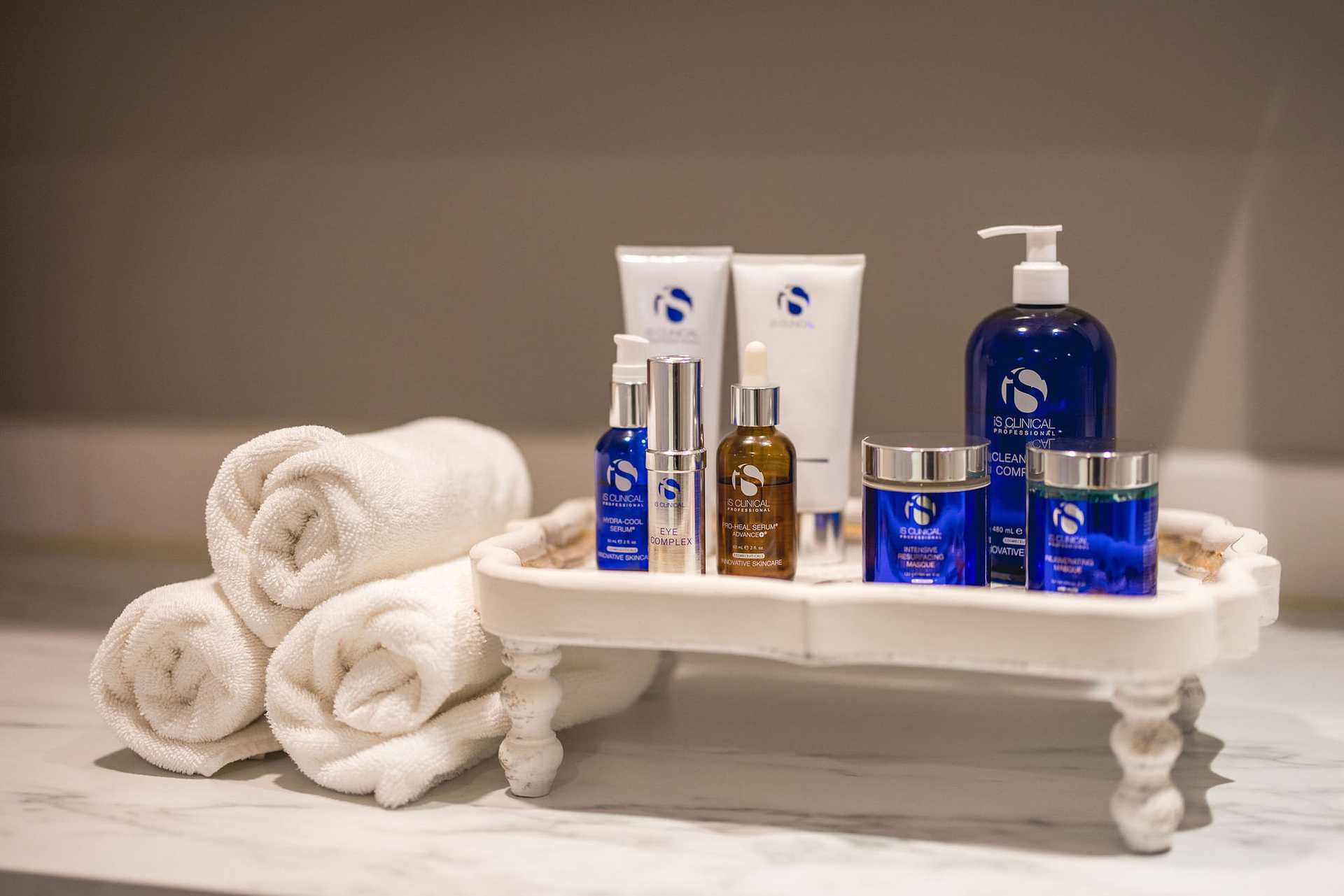 Skincare products and towels arranged neatly on a white tray on a bathroom counter.
